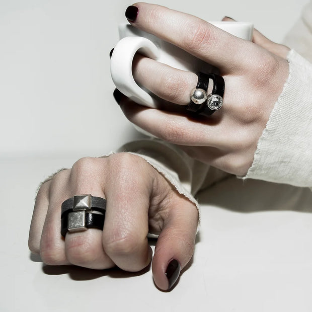 Person wearing multiple rings, including silver square detail ring